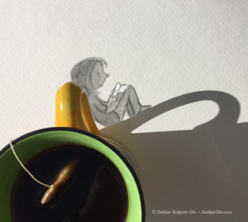 A mug of tea seen from above, with a tea bag string visible. The mug’s handle casts a shadow that aligns with a pencil drawing of a seated child reading a book, creating the impression of the child sitting against the mug’s shadow.