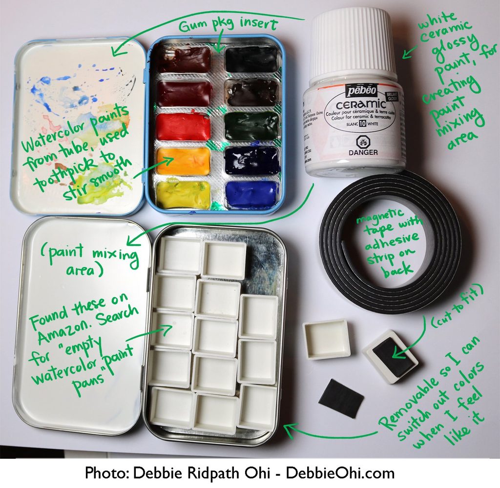 A photo showing two open metal mint tins being used to make DIY travel watercolor kits, labeled with handwritten green notes pointing to various components. One tin holds filled watercolor pans with an inserted gum package cover, while the other contains empty watercolor pans serving as a paint-mixing area. Next to the tins are a bottle of white ceramic paint, a roll of magnetic tape with an adhesive strip on the back, and smaller cut-to-fit magnetic pieces. Copyright DebbieOhi.com is visible at the bottom right.